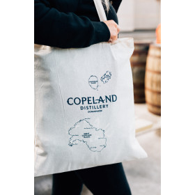 Copeland Distillery Tote Bag hanging on a person's shoulder.