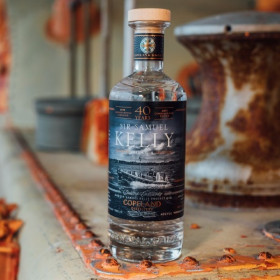 A bottle of Sir Samuel Kelly Gin from Copeland Distillery sitting on the deck of a ship.